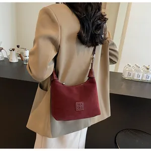 Borsa hobo vintage in pelle scamosciata bordeaux con toppa logo su un modello chic