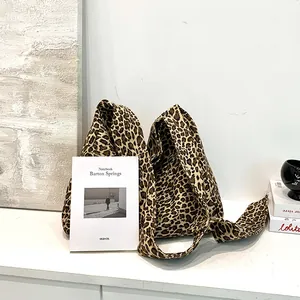 Close-up view of a leopard print cotton tote bag styled with books in a minimal studio.