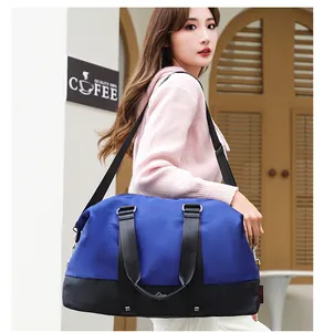 Detailed view of large blue travel duffel bag carried by model in outdoor setting