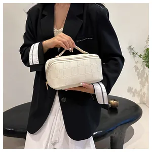 Detailed shot of a cream-white checkered handheld cosmetic storage bag held by a model