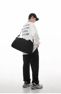 Man carrying a large black duffle bag for gym and travel use in a studio setting