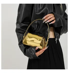 Vista dettagliata di una mini borsa baguette dorata metallizzata tenuta da una modella