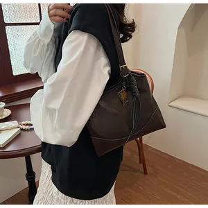Detailed view of dark brown vintage tote bag with decorative charm and green cord