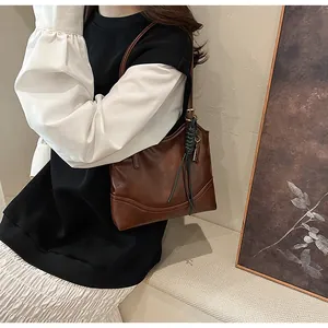 Detail view of a vintage brown leather underarm bag worn with a stylish outfit.