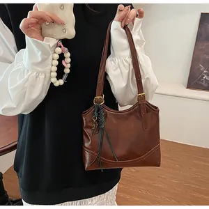 Detailed shot of vintage brown leather tote bag held by model in stylish casual outfit