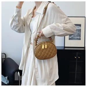 Close-up view of a stylish brown quilted oval handbag featuring a unique scrunchie handle.