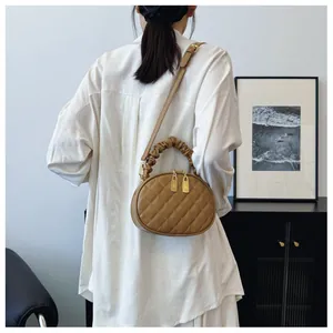 Elegant khaki quilted crossbody handbag with ruffled handle worn by model in white