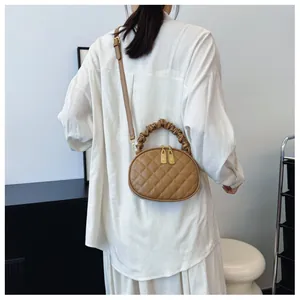 Back view of a stylish woman wearing a khaki quilted crossbody bag with a ruched handle