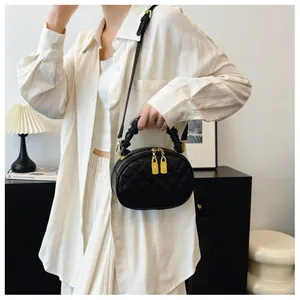 Model wearing a black quilted oval handbag with a versatile ruched handle and gold zippers.