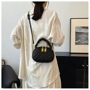 Stylish black quilted crossbody bag with a ruched handle and golden zippers in use.