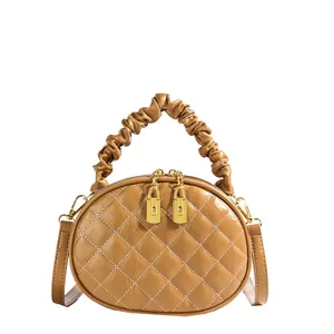 Detail shot of tan quilted handbag with scrunchie handle and gold zippers for women.