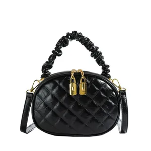 Detailed view of the black quilted handbag with unique ruffled top handle and gold zippers.