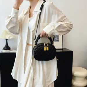 Black quilted crossbody bag with gold hardware and ruched handle carried by model.