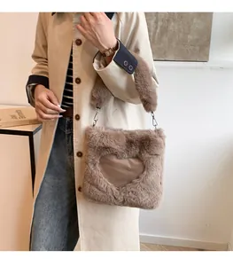 Primo piano di una borsa tote in peluche marrone con motivo a cuore tenuta da una persona.