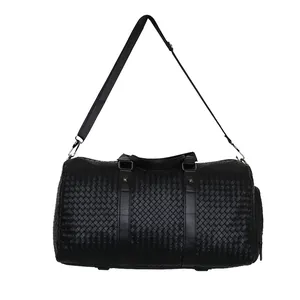 Détail d'un grand sac de voyage noir tissé avec poignées et bandoulière amovible.