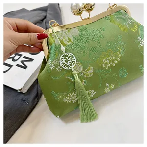 Primer plano de un bolso bordado chino verde vintage con cierre de perlas blancas