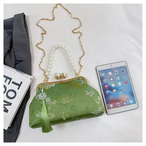Bolso chino bordado verde elegante con asa de perlas y detalle de borla decorativa.
