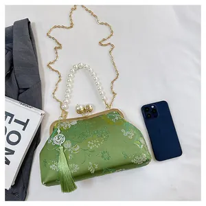 Detalle de bolso chino bordado verde con asa de perlas y elegante colgante de borla