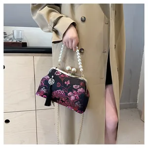 Detalle de bolso bordado vintage chino con asa de perlas y elegante borla de seda