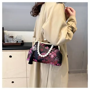Bolso vintage bordado de flores con asa de perlas y cadena dorada en un modelo