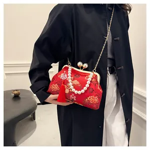 Detalle del bolso rojo bordado de estilo chino con asa de perlas y cadena dorada