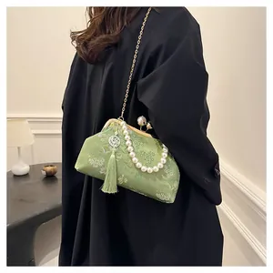 Vista detallada de un bolso bordado de estilo chino verde con asa de perlas y borla.