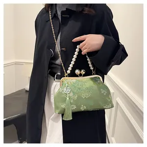 Modelo que lleva un bolso bordado verde con asa de perlas en un elegante estilo retro chino