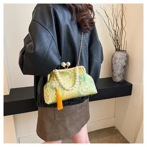 Detalle de bolso chino vintage bordado con asa de perlas y cadena dorada
