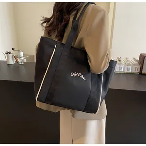 Vista lateral de un elegante bolso tote negro de gran capacidad llevado por una estudiante