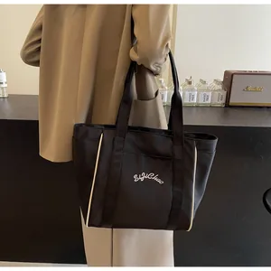 Bolso tote de nylon negro de gran capacidad con bordado en el hombro de la modelo
