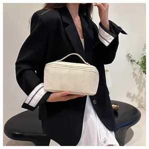 Elegant beige checkered square cosmetic bag with handle shown in lifestyle context