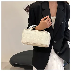 Detailed view of a white woven checkerboard handbag held by a fashion model in a blazer