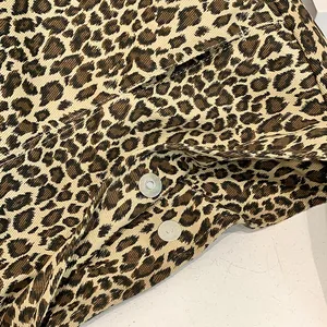 Macro view of leopard print cotton fabric and metallic magnetic snap button detail.