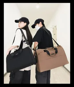 Zwei Models tragen große schwarze und khakifarbene Reisetaschen in einem Flur