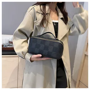 Detailed view of the black checkered square handbag held by a model in a trench coat