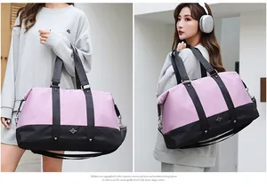 Detail shot of a stylish pink and black large capacity travel duffel bag carried by a model