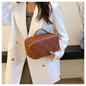 Detailed shot of brown checkered handbag held by model in professional white blazer