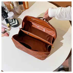 Interior detail of a large brown checkered cosmetic bag showing three compartments