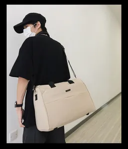 Professionelles Modell trägt eine große beige Reisetasche über der Schulter im Haus