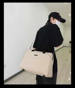 Detailansicht einer großen beige Reisetasche, die von einem Model getragen wird.