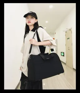 Asiatisches weibliches Model trägt eine große schwarze Reisetasche in einem Flur
