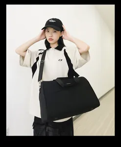 Große schwarze Reisetasche für Sport oder Business, getragen von einem Model im Flur.