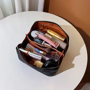 Large checkered black square cosmetic bag with orange lining and internal compartments.