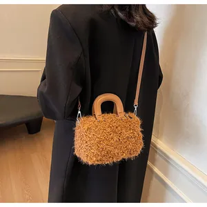 Rear view of stylish brown fuzzy plush crossbody box bag with tan leather handles and strap.