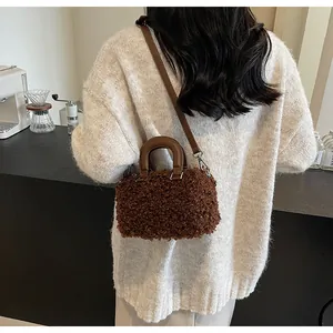 Close-up detail of a brown plush crossbody box bag worn with a cream sweater.