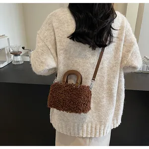 Detail of a brown furry plush crossbody box bag styled with a beige knit sweater