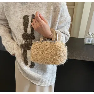Close-up detail of a stylish beige fuzzy plush mini handbag held by a fashion model