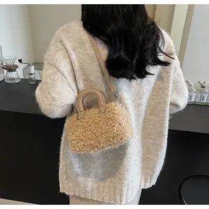 Detail shot of a cream-colored plush faux fur box bag styled with a white knit sweater