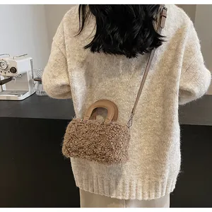 Detail view of a stylish brown plush box handbag with leather handles and strap