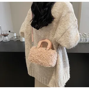 Close-up detail of a pink plush box handbag with a detachable strap and top handle.